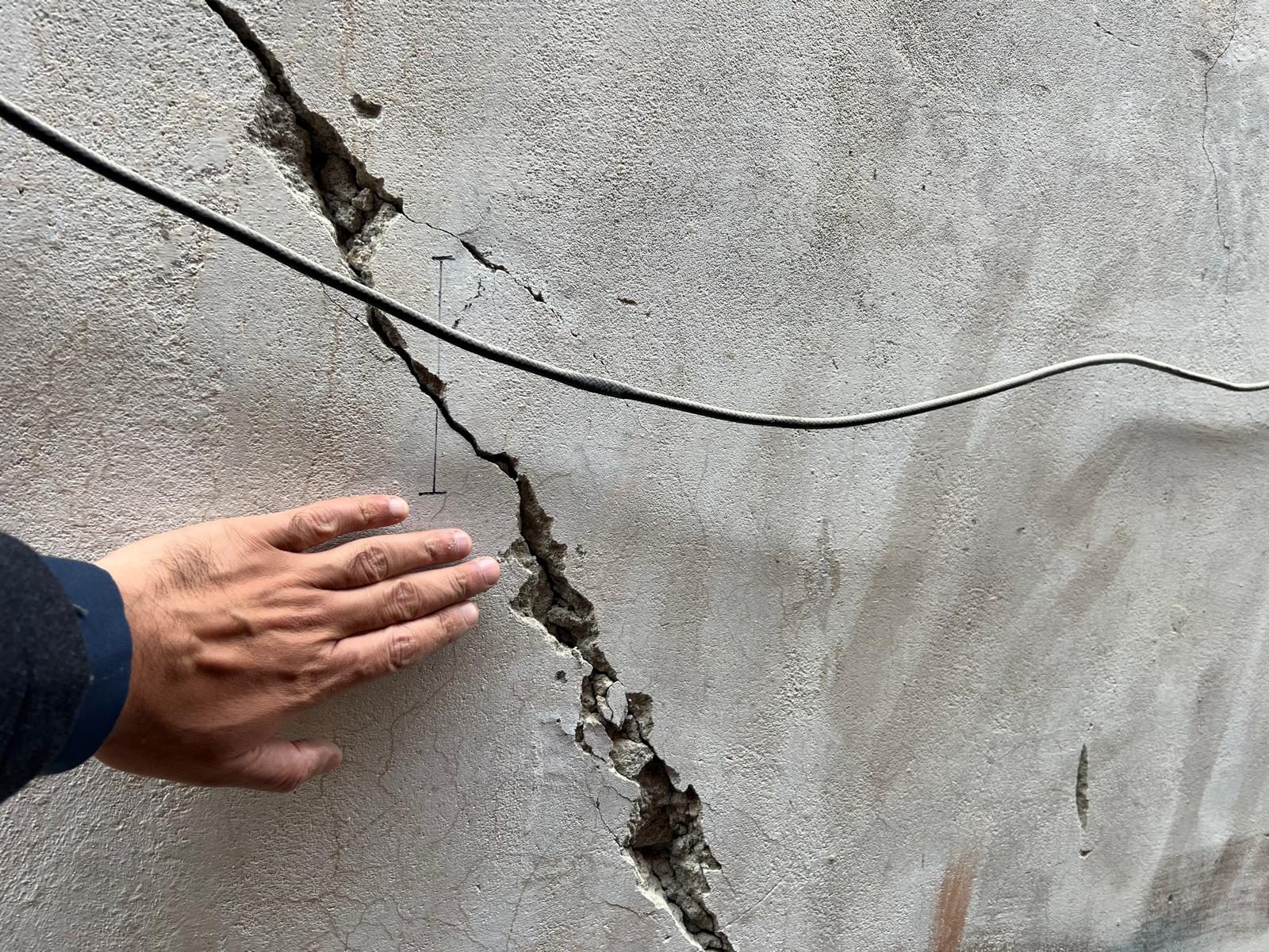 Close-up of a wide wall crack being measured
